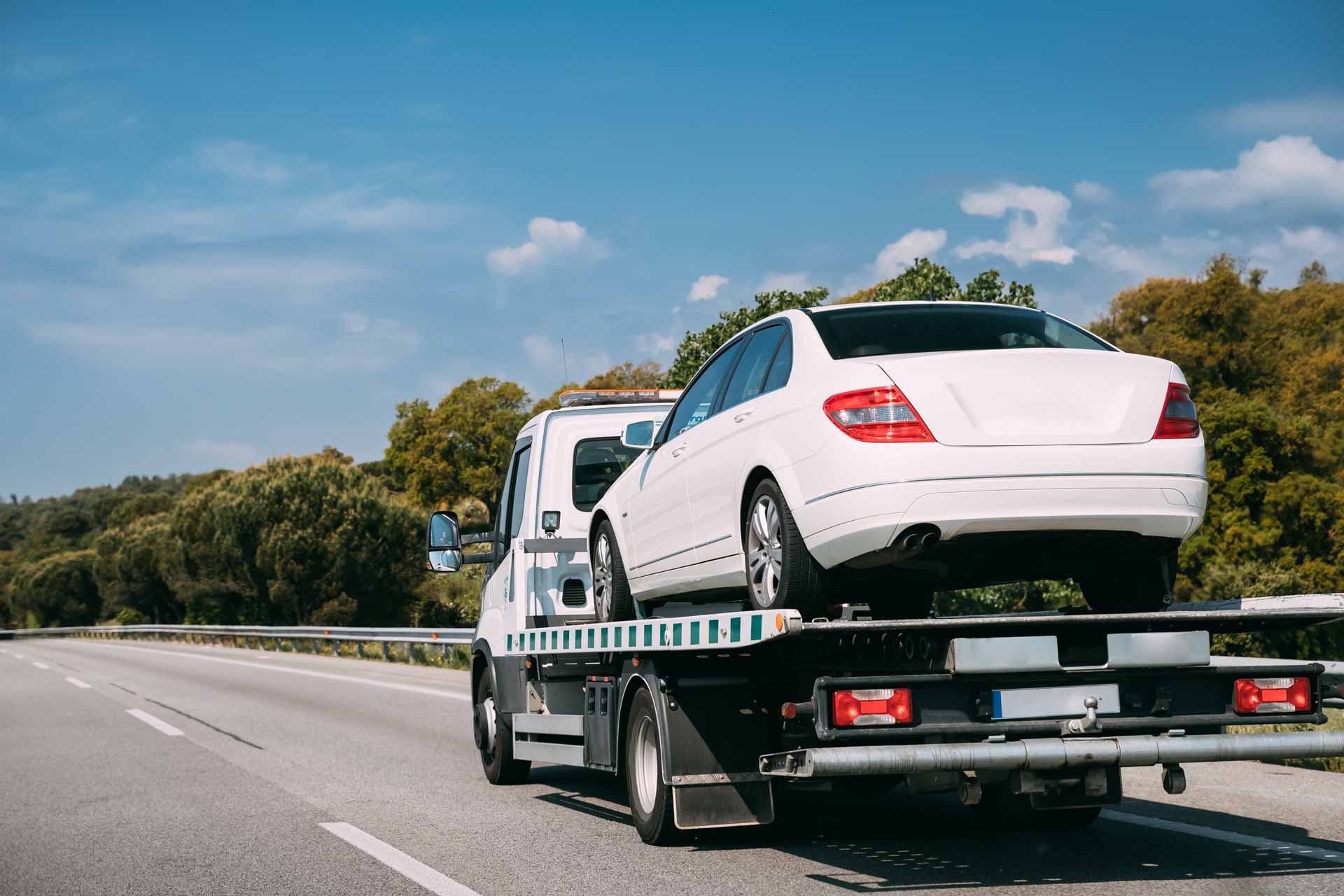 A recovery truck transporting a vehicle on the road